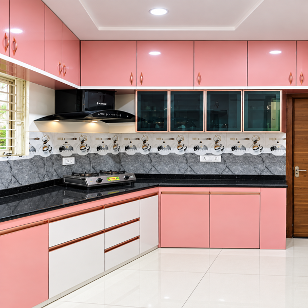 Pink modular kitchen, modern kitchen, contemporary kitchen, modular kitchen design, L shaped kitchen, pink kitchen cabinets, pastel pink cabinets, kitchen interior, Indian kitchen design, modern Indian kitchen, black granite countertop, dark countertop, kitchen backsplash, patterned backsplash, decorative tiles, floral backsplash, kitchen chimney, chimney hood, gas stove, cooktop, glass cabinet doors, overhead cabinets, base cabinets, kitchen drawers, cabinet handles, rose gold handles, white lower cabinets, two tone kitchen, pink and white kitchen, modern cabinetry, modular storage, kitchen organization, compact kitchen, spacious kitchen, residential kitchen, apartment kitchen, home interior, interior design, kitchen decor, contemporary home, luxury kitchen, stylish kitchen, pastel interior, soft pink decor, marble floor, glossy floor tiles, window kitchen, natural light, ventilation window, wall cabinets, kitchen counter, countertop design, sink area, cooking area, kitchen workspace, functional kitchen, custom kitchen, bespoke cabinetry, premium kitchen, elegant kitchen, clean kitchen, modern appliances, black chimney, kitchen exhaust, kitchen lighting, ceiling lighting, recessed lights, false ceiling, geometric backsplash, patterned wall tiles, ceramic tiles, backsplash design, cabinet design, drawer design, handle design, interior styling, home renovation, kitchen makeover, Indian home interiors, modern home design, residential interior, sleek kitchen, minimalist kitchen, contemporary styling, warm lighting, bright kitchen, functional storage, efficient kitchen, kitchen inspiration, home decor ideas, kitchen design ideas, modular kitchen cabinets, designer kitchen, modern countertop, premium interiors, pastel kitchen design, stylish cabinetry, kitchen photography, elegant home, practical kitchen.